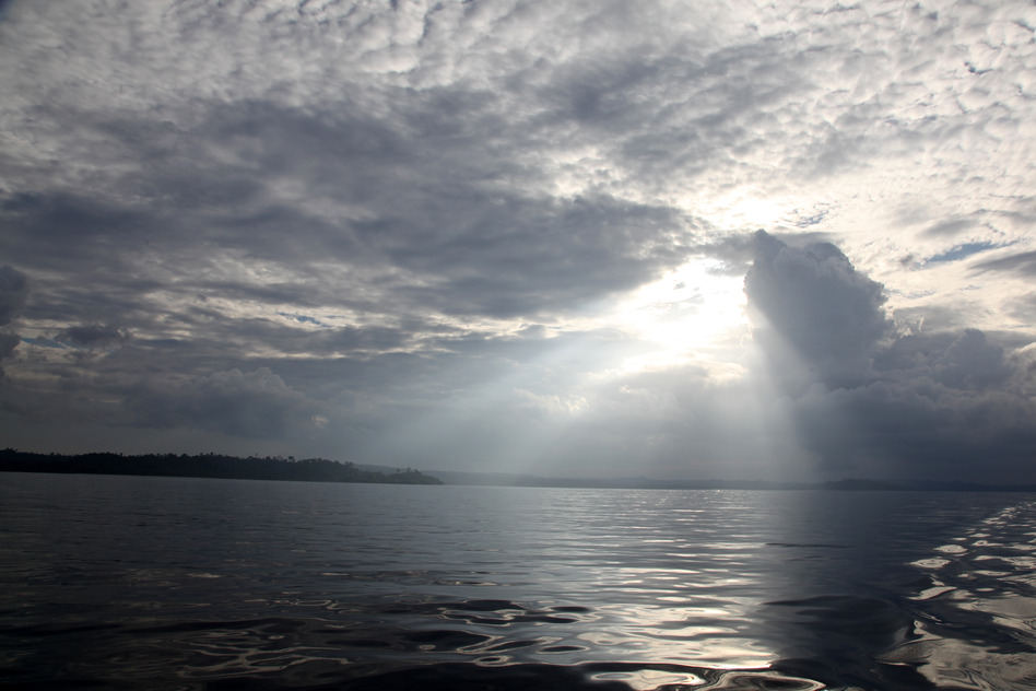 The sun peers through storm clouds on a still afternoon in the Mentawai Islands - Indonesia