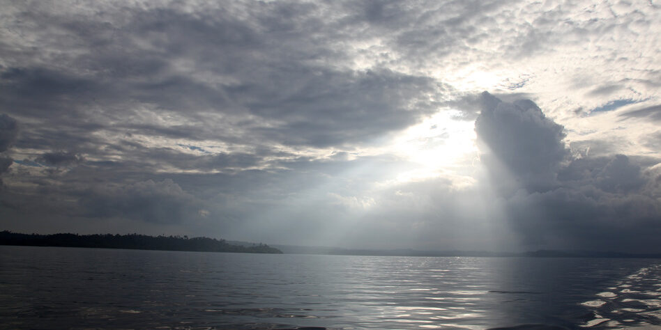 The sun peers through storm clouds on a still afternoon in the Mentawai Islands - Indonesia